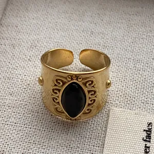 Close-up of vintage gold-tone adjustable ring with oval black gemstone inlay.