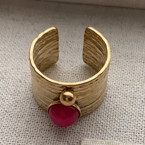 Close-up of vintage gold open ring featuring a vibrant pink gemstone and textured finish.
