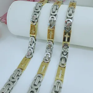 Detailed close-up of two-tone stainless steel Byzantine chain with cross engravings