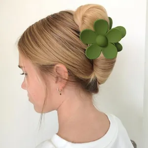 Detail view of a large olive green matte flower hair claw clip styled in a blonde bun.