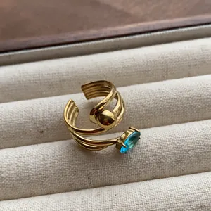 Macro shot of elegant gold adjustable ring with blue gemstone on beige velvet jewelry tray