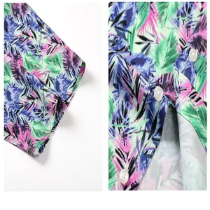 Close-up of vibrant tropical leaf print and white buttons on Hawaiian beach shirt.