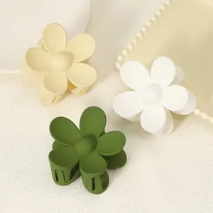 Close-up detail of three elegant matte flower-shaped hair claws in yellow, white, and green
