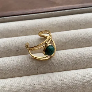 Detailed close-up view of a vintage gold open ring featuring a polished green gemstone