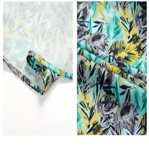 Detailed macro view showing tropical leaf print and hem stitching of a beach shirt