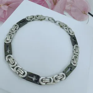 Detail view of a stainless steel men's necklace with cross-engraved black links