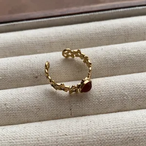 Close-up of a vintage gold-colored star-patterned open ring with an oval red gemstone.