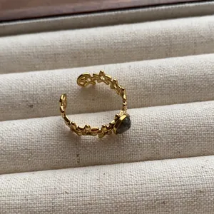 Close-up detail of vintage gold open ring featuring oval grey gemstone on linen background