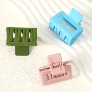 Macro detail showing three matte square hair claw clips in blue pink and olive green tones