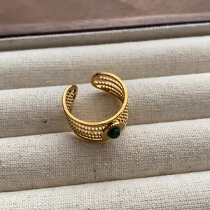 Detailed macro view of vintage gold textured grid ring with green gemstone inset