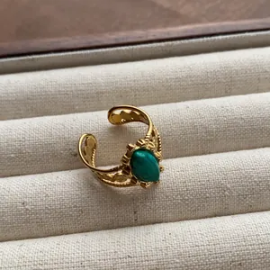 Detailed macro view of vintage gold-plated open ring with an oval green gemstone.