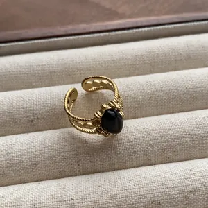Close-up detail of a vintage gold open ring featuring a polished oval black gemstone.