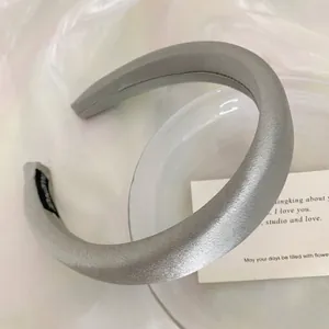 Close-up detail of a minimalist gray satin sponge headband featuring a high skull top design