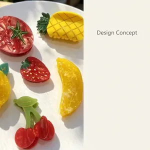 Detail of fruit-shaped acetate hair clips with vibrant strawberry and pineapple designs