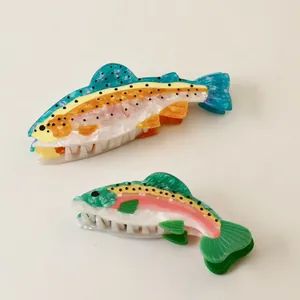 Detailed shot showing two vibrant acetate fish-shaped hair claw clips for women