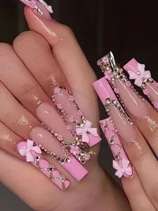 Close-up detail of pink 3D bow and flower nail art charms on long coffin press-on nails