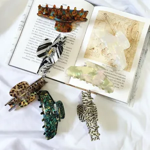 Selection of large French acetate hair claws in various patterns on an open book