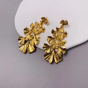 Vintage matte gold statement earrings with layered ginkgo leaf dangle design on white display