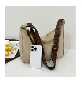 Sac bandoulière rétro en daim beige pour femme montrant la taille avec un smartphone