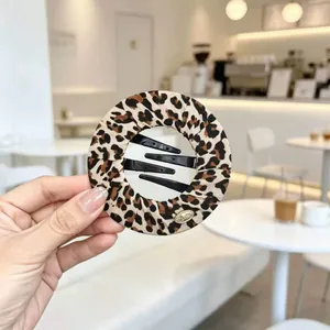 Elegante fermaglio per capelli piatto circolare con stampa leopardata in un ambiente di caffè