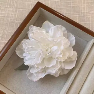 Gros plan détaillé d'une pince à cheveux en tissu pivoine de style antique dans un coffret