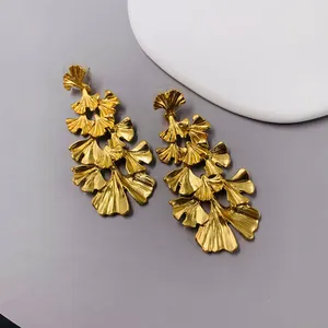 Elegant matte gold tiered ginkgo leaf dangle earrings with a vintage revival aesthetic.