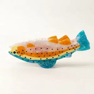 Side view detail of a colorful salmon-shaped acetate hair claw clip for women's hairstyling