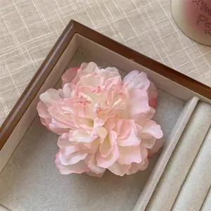 Vue détaillée d'une élégante pince à cheveux en pivoine rose et blanche dans un plateau.
