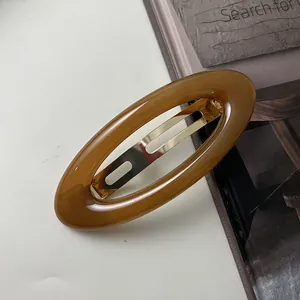 Close-up of vintage amber acrylic hair clip with gold metal spring mechanism