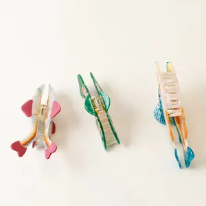 Detailed top view of three colorful fish-shaped acetate hair claw clips for women