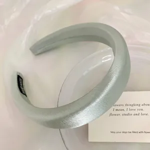 Detailed close-up of a mint green satin padded headband with high cranial top design