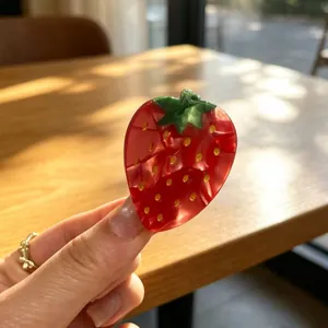 Detailed view of red strawberry acetate hair claw clip with glossy marbled finish