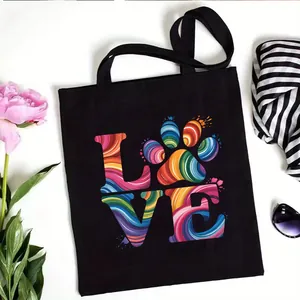 Black canvas tote bag featuring a colorful paw print LOVE graphic for daily shopping