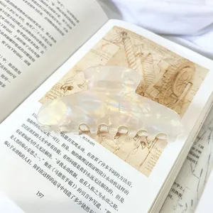 Detailed view of an elegant large iridescent pearl hair claw clip on a book.