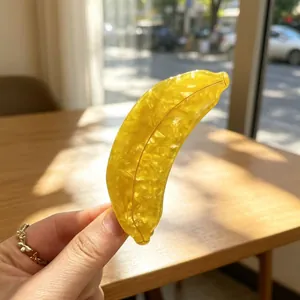 Detailed view of a yellow acetate banana-shaped hair claw clip in natural sunlight