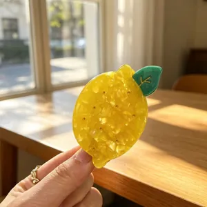 Close-up of a vibrant yellow lemon-shaped acetate hair claw clip in natural sunlight