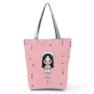 Detail view of pink tote bag featuring a cute cartoon nurse print and gray straps