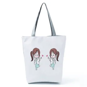 Close-up of a white canvas tote bag featuring cute cartoon nurse prints and gray handles