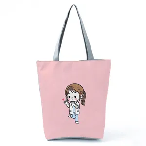 Detailed view of pink tote bag with cute nurse cartoon print and gray handles