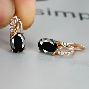 Close-up of champagne gold earrings with oval black gemstones and sparkling accents
