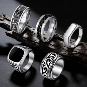 Detail shot of five vintage stainless steel rings for men with diverse engravings.