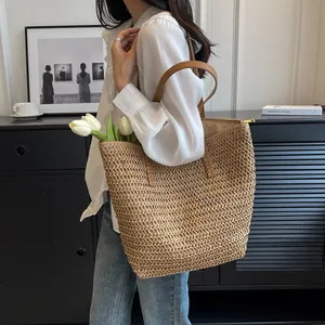 Handmade woven straw tote bag with brown straps shown in a lifestyle indoor setting