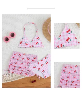 Close-up detail of girls pink gingham three-piece swimsuit with sweet cherry pattern