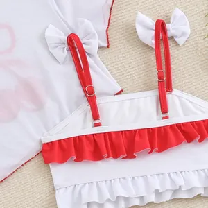 Close-up detail of a children's cherry swimsuit featuring red straps and white ruffles