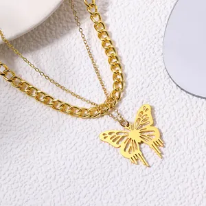 Close-up of gold-plated hollow butterfly pendant with layered curb chain necklace.