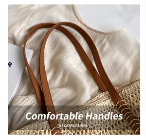 Close-up detail of sturdy brown faux leather handles on a woven straw beach tote bag