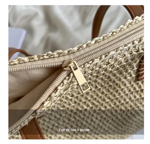 Close-up detail showing the smooth metal zipper and woven texture of the straw beach bag