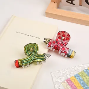Detail view of creative pencil-shaped hair claws in green stripes and pink polka dots