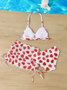Detailed view of girl's strawberry print 3-piece swimwear including top, bottom and skirt.