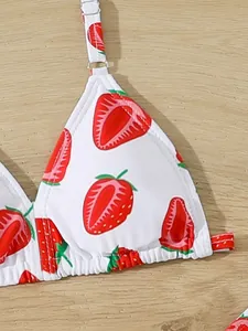 Close-up detail of children's bikini top with vibrant red strawberry print pattern